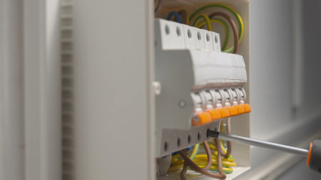 Electrician assembles electrical panel. Close up of a man hands tightening screw with a screwdriver...