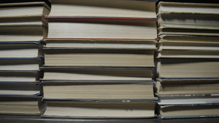 Stacks of books in color covers lying on the table in the library. Rows of old books. Literature. Textbooks for learning, gaining knowledge, education at school, college or university. Close up.の写真素材
