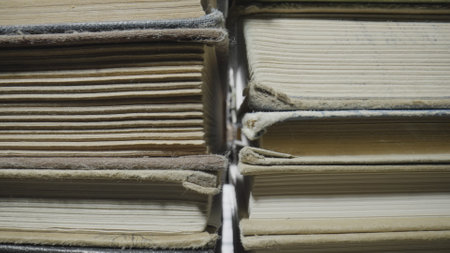 Stacks of books in shabby gray covers lying on table in the library. Rows of old books. Literature. Textbooks for learning, gaining knowledge, education at school, college or university. Macro shot.の写真素材