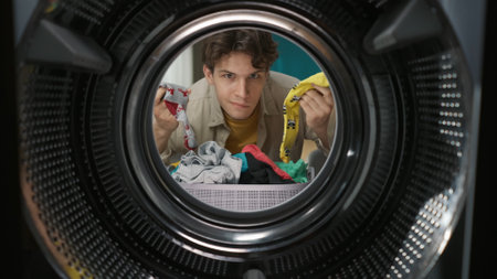 View from inside the washing machine, adult man looking confused holding a different socksの写真素材