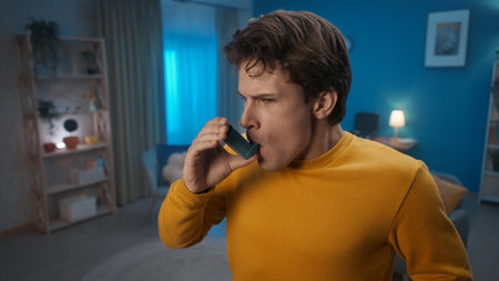 A man uses an asthma inhaler in the living room at home close up. Fight allergies, asthma. Home medicine concept.の写真素材