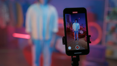 Smartphone display, man blogger standing in front of the camera and filming a video for social networks at home.の写真素材
