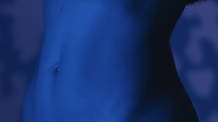 Close up shot of a thin females wiaist in an evening atmosphere, blue color scheme and shadowed background.の写真素材