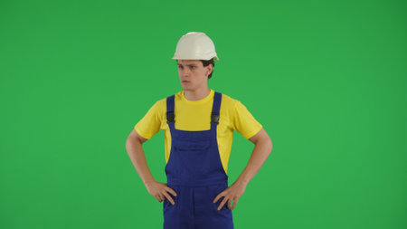 Medium green screen isolated chroma key shot of a young construction worker looking around with his hands on his hips.の写真素材