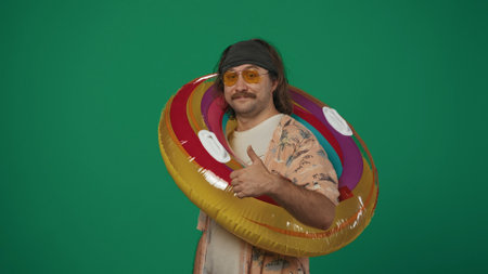 Man in casual clothing wearing inflatable tube ring over shoulder looking at the camera showing...