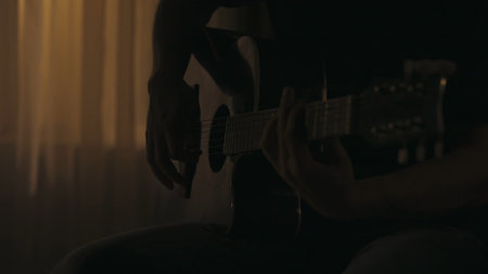 Closeup shot of a man playing song on the acoustic guitar using guitar pick. Everyday life creative concept.の写真素材