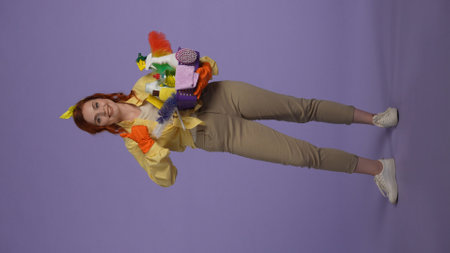 Vertical photo. Woman in casual clothing and rubber gloves with smiling face holding basket with...