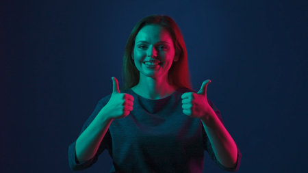 Portrait of a young redhaired woman in a studio on a blue background in pink and green neon light...