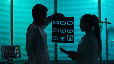 Medium-sized silhouette shot of two doctors standing in a hospital ward. Doctors look at patients...