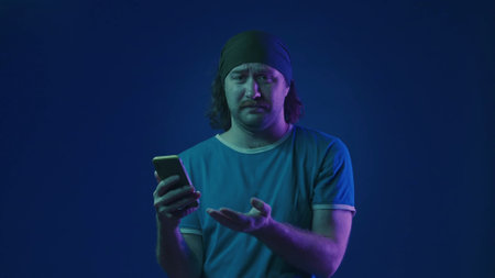 The man points to his smartphone with disappointment. The man lost in an online game. A man with a...