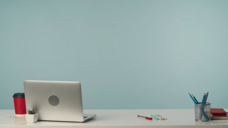 Isolated background shot of a working surfase, a desk with a laptop, cup of coffee, plant and other working supplies.の写真素材