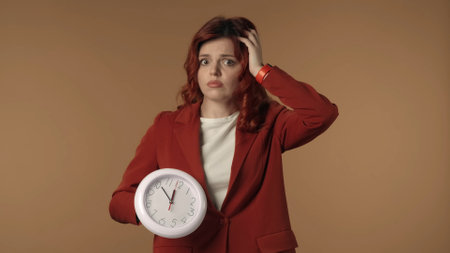 Medium isolated shot of a shocked and worried young woman looking at the clock and holds on to her head.の写真素材