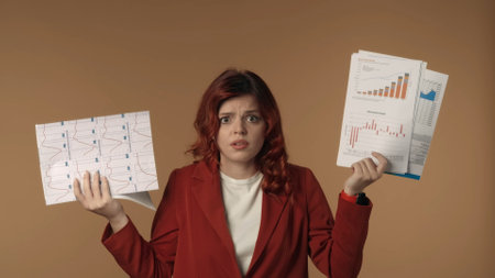 Medium isolated shot of a stressed and nervous young woman looking at the camera with a bunch of paperwork in her hands. She is shrugging, overwhelmed.の写真素材