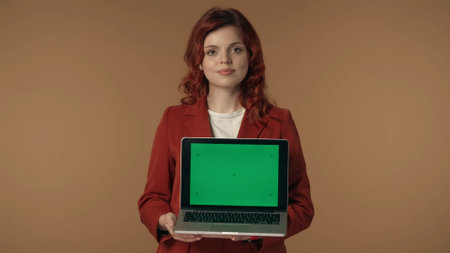 Medium isolated shot of a young woman smiling and holding a laptop with advertising area, workspace mock up.の写真素材