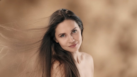 In the frame is a middle-aged woman with long, dark hair. Turning slightly to the side, she looks at the camera and smiles. The wind is blowing on her developing the hair that covered her faceの写真素材