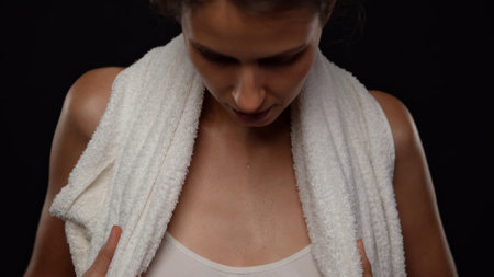 Closeup shot of beautiful caucasian woman body in twhite top with towel over shoulders, wet skin with water drops after shower or sport.の写真素材