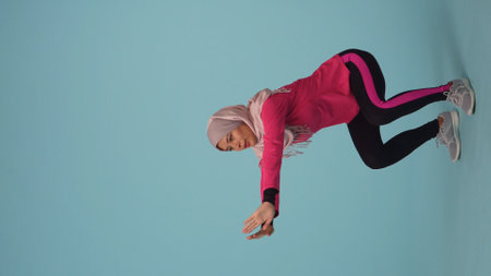 Full-sized isolated photo capturing an attractive young woman wearing a sportswear and a hijab,...