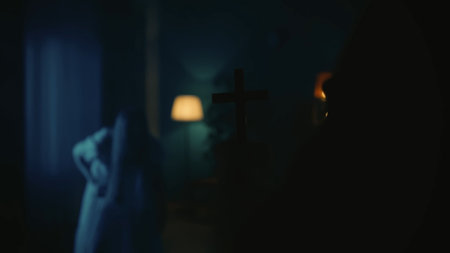 Shot of a priest approaching a possessed female, ghost, entity. The exorcist holds a cross in hand, scaring the paranormal creature away.の写真素材