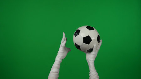 Detail green screen isolated chroma key photo capturing mummys hands raising a football, checked ball up in the air, throwing it from hand to hand.の写真素材