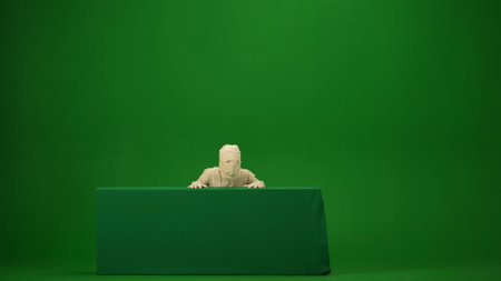 Green screen isolated chroma key photo capturing a mummy rising and peeking from behind a green screen banner box. Mock up, workspace for your promotion clip or advertisement. Full lengthの写真素材