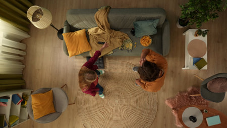 Top view capturing a young couple standing in the middle of the room. Woman is scolding at her partner about the mess he left on the couch.の写真素材