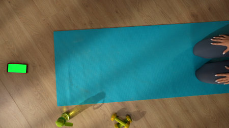 Top view capturing an unrecognizable woman sitting on a mat in front of a smartphone with an advertising area, workspace mock up on it. Home, room, indoor activities.の写真素材