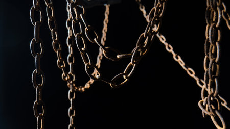 Macro shot of a rusty old metal chain on a black background. The chain links are covered in rust and...