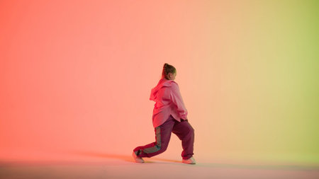 Attractive woman dancing jazz-funk on red and green neon background in a studio. Modern dynamic and energetic dance choreography. Full length.の写真素材