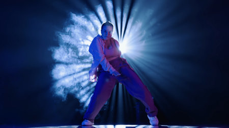 Silhouette of a woman dancing jazz-funk in a studio. Black background filled with smoke, white...