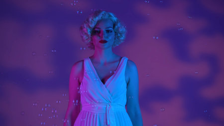 Portrait of a cheerful woman looking like Marilyn Monroe surrounded by soap bubbles close up. Woman...