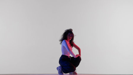 Attractive woman in white top black pants and in red and blue neon light sitting on the floor,...