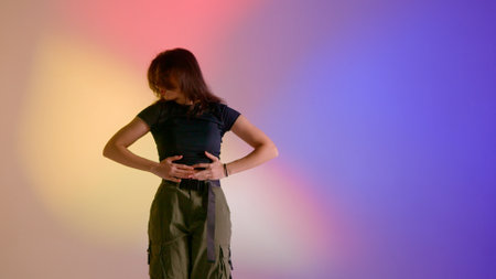 Attractive woman in top and khaki pants posing at camera close up shot, dancing jazz funk choreography in studio, isolated on neon background.の写真素材