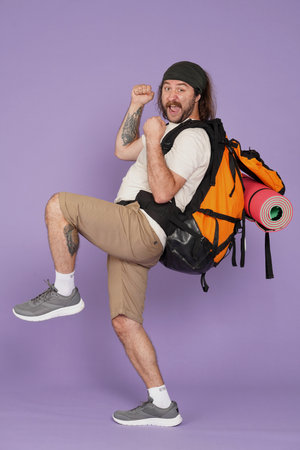 Man tourist in casual with backpack posing with hands up on one leg, happy expression. Isolated on...