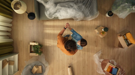 Top view of apartment living room. Man and woman dancing together in the room with packed furniture and boxes with stuff.の写真素材