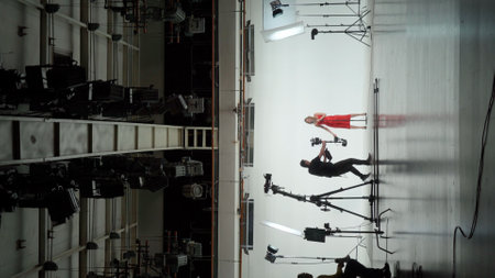 Professional filming pavilion with a white cyclorama. Shooting of a girl in a red dress who sings...