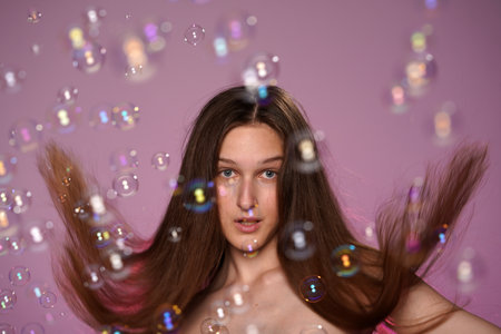 Portrait of seminude woman with long hair surrounded by soap bubbles in closeup. Woman in studio on...