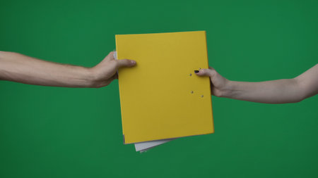 In the shot close up on a green background, chromakey. The woman holds in her hand a yellow folder...
