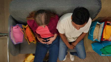 Top view of modern apartment living room. Close up shot of young man and girl sitting on the sofa,...
