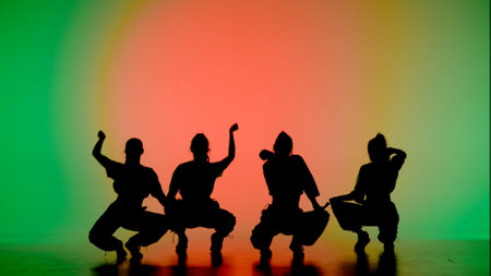 In the frame on a green, orange background, gradient. Dancing group consisting of attractive, girls, in silhouette. They demonstrate dance moves in the direction of jazz funk. They are rhythmicの写真素材