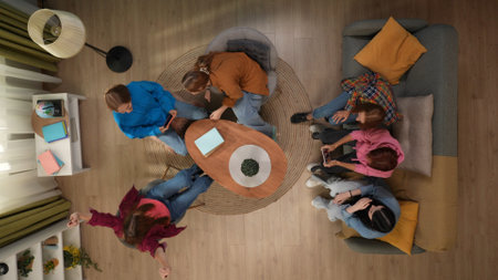 Top view of a group of girl students sitting in the living room. The girls, divided into teams, are...
