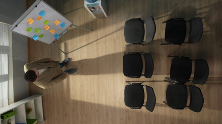 In the picture above there is a middle aged man in an empty room, an auditorium. He is waiting for...