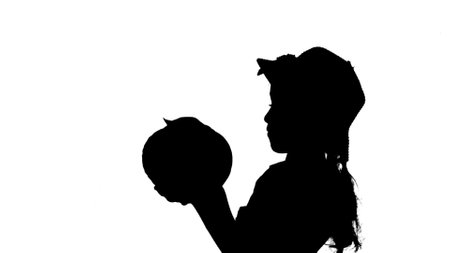 Portrait of farmer isolated on white background with alpha channel. Silhouette of little girl gardener in hat standing and holding big cabbage.の写真素材