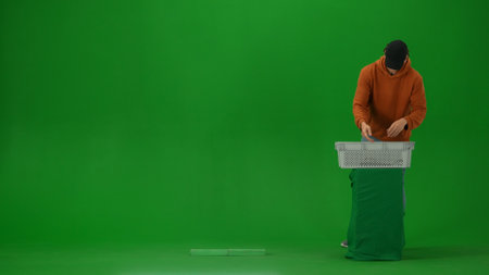 Portrait of person tourist isolated on chroma key green screen background. Young man preparing to go through metal detector at airport puts stuff in basket.の写真素材