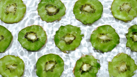 Slice of kiwi underwater or in water with splashing and droplet top view flat lay on white background.の写真素材