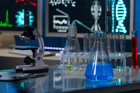 In the close up shot, the laboratory room is shown. On the table there is a microscope, test tubes and flask with blue liquid. Background computer monitor enabled. There are no people in the frameの写真素材
