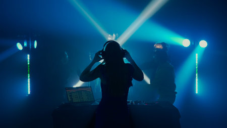 Female DJ Leading the Party at Nightclub with Crowd in Silhouetteの写真素材