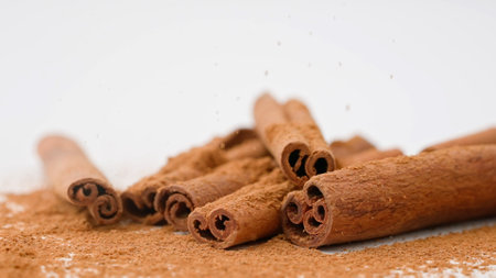 Close up studio shot of food ingredient. A pile of brown dried cinnamon sticks laying on the white...