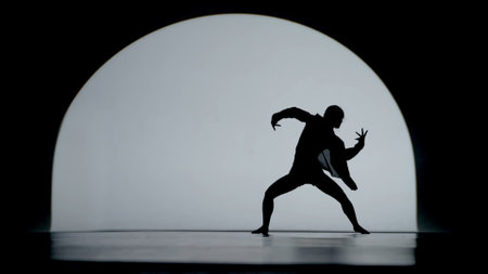 Contrasting silhouette of a young woman performing contemporary dance in the studio. Female figure dancing under a spotlight. Full size.の写真素材