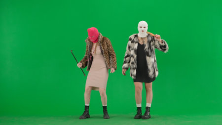 Two women in white and pink balaclavas dancing funny with a bat and a crowbar. Freak women in fur...