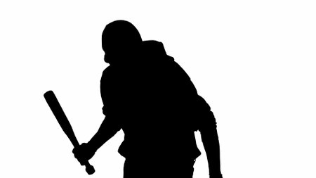 Black silhouette of thief on isolated white background. A male robber in hoodie and balaclava walks with a wooden club in his hands, preparing to commit a crime. Half-turn.の写真素材